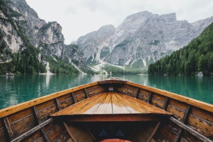 travel - brown wooden boat moving towards the mountain